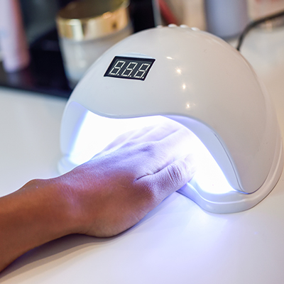manicured nails in uv lamp in beauty salon.